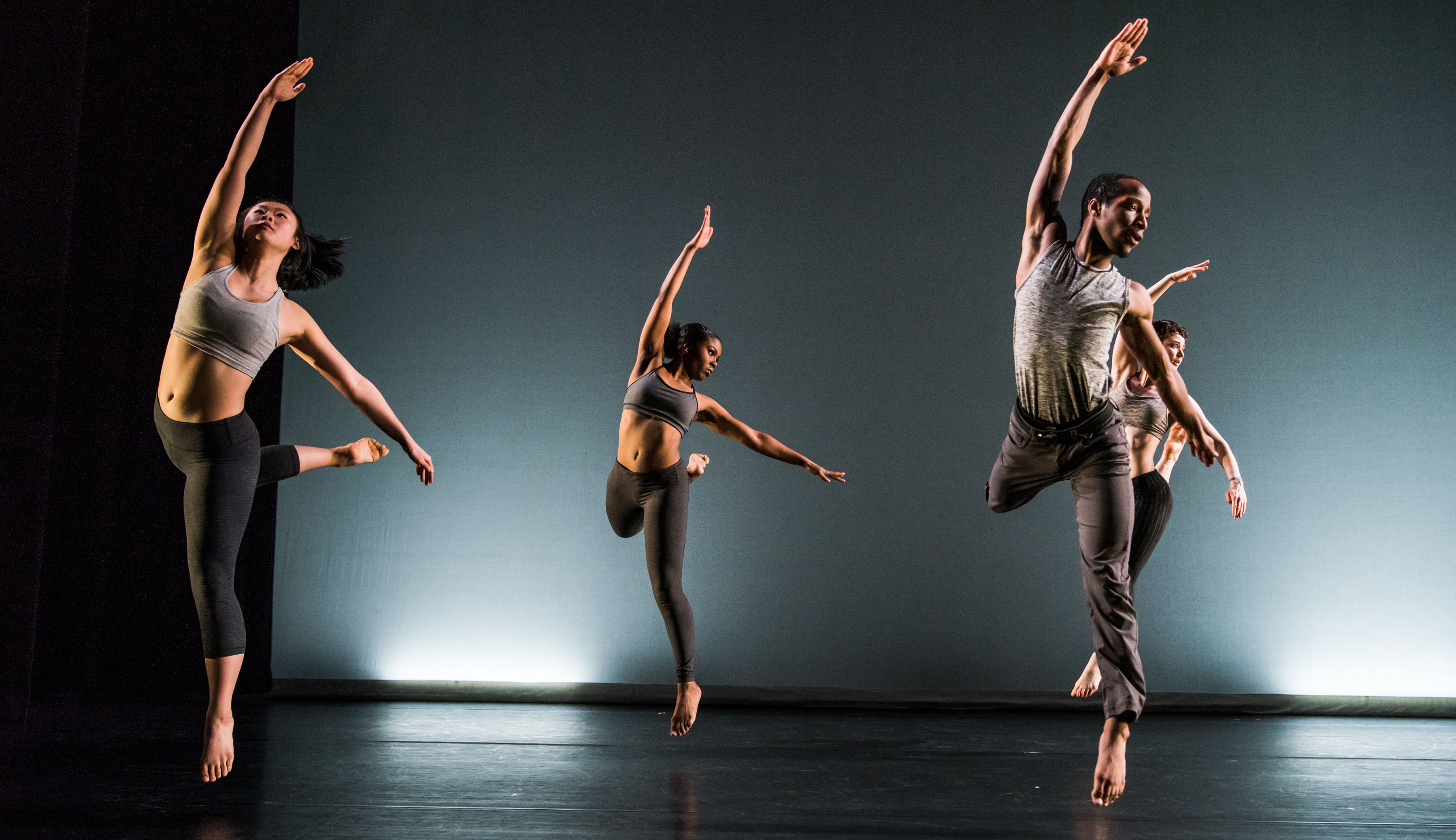 Four students dance on a bare stage at UMBC