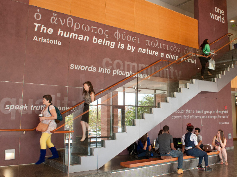 Students in front of a wall of inspirational quotes in UMBC's Public Policy Building.